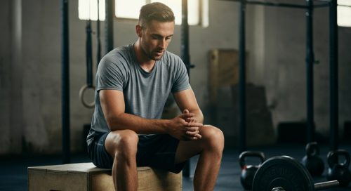 Ein Hardgainer betrachtet nach dem Crosstraining zufrieden seine Fortschritte in einer Crossfit Box.