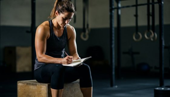Fokussierte Athletin in einer Cross-Training-Box, die ihren Crosstraining Trainingsplan erstellt.
