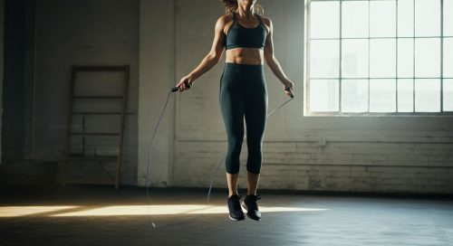 Eine Athletin in einer minimalistischen Halle konzentriert sich beim Double Unders lernen.