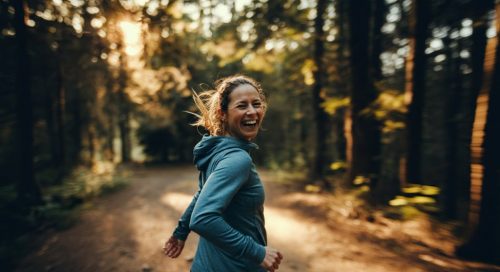 Eine Läuferin hat sichtlich Spaß bei ihrem Fartlek Training auf einem Waldweg.