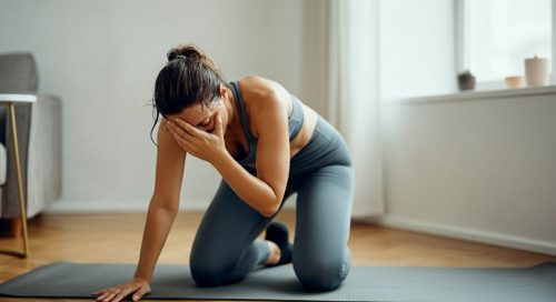 Eine Frau macht nach anstrengenden HIIT Core Übungen eine kurze Pause auf ihrer Matte und blickt zufrieden.