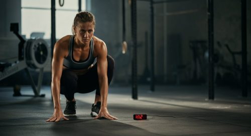 Fokussierte Athletin blickt auf eine Stoppuhr, um ihr Training nach strukturierten HIIT Protokollen zu starten.