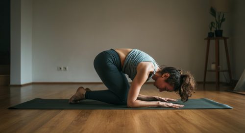 Eine Frau macht konzentriert HIIT Rückenübungen zu Hause in der Bird-Dog-Position für einen starken Rücken.