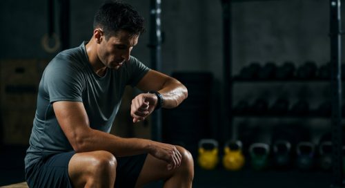 Erschöpfter Athlet analysiert nach dem Workout die Daten seiner Pulsuhr für Crosstraining.