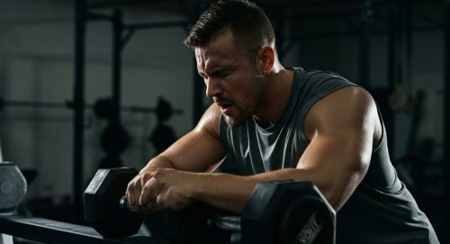 Ein Athlet macht eine kurze Pause während seines intensiven Rest-Pause Trainings im Fitnessstudio.